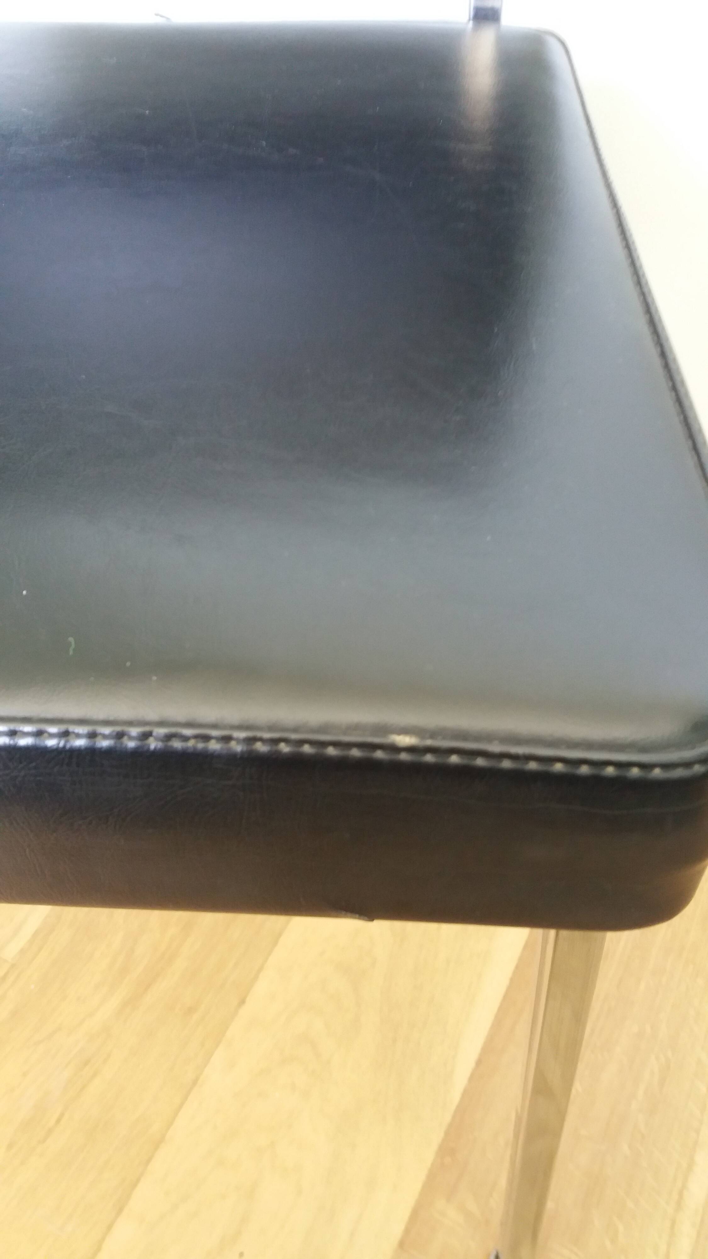 Chrome metal chairs and black faux leather upholstery in retro modernist style.