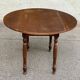 Round kitchen or dining table with extendable leaves in dark wood.
