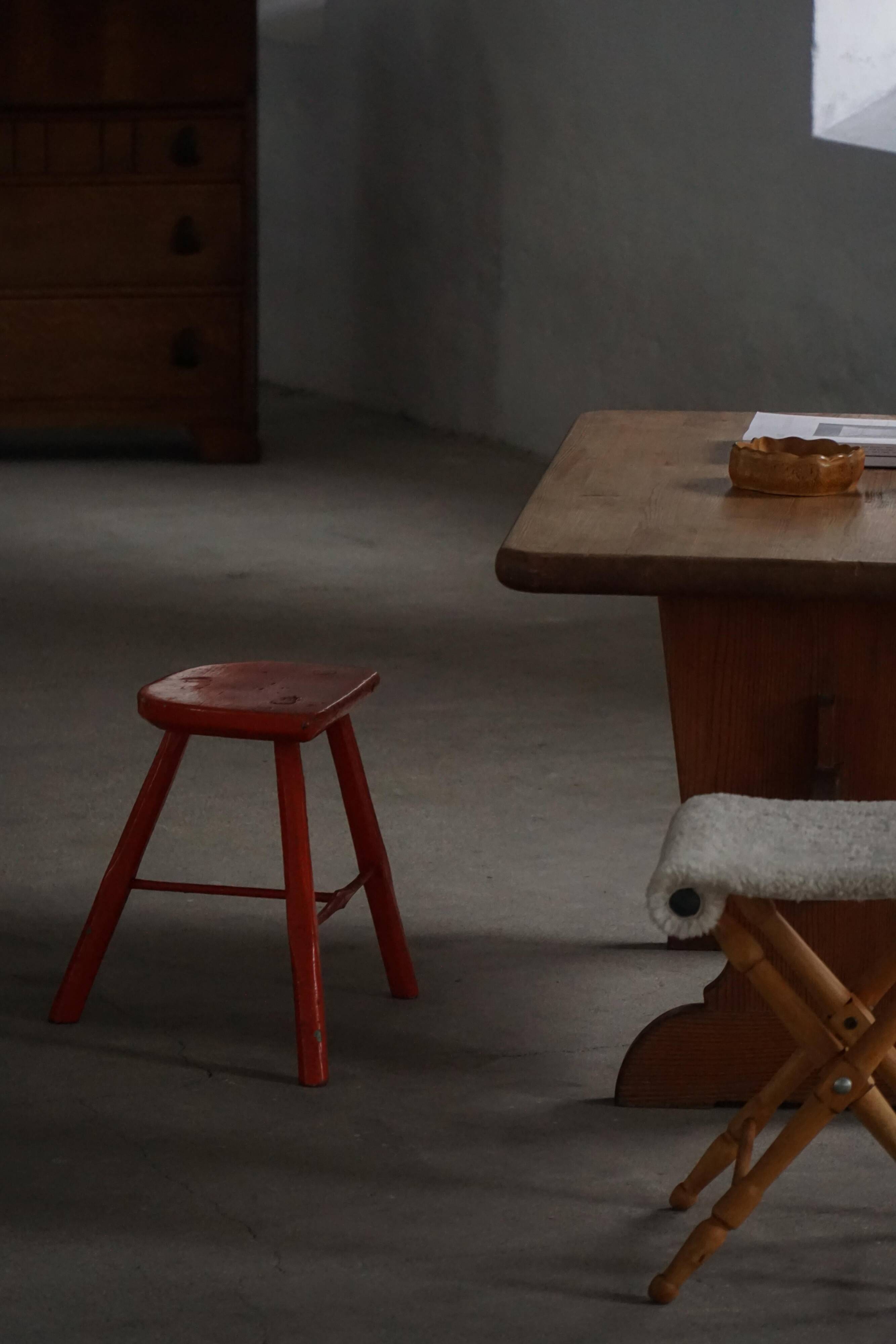 Pair of wooden stools painted in patinated red with flared legs, 1950s-1960s.
