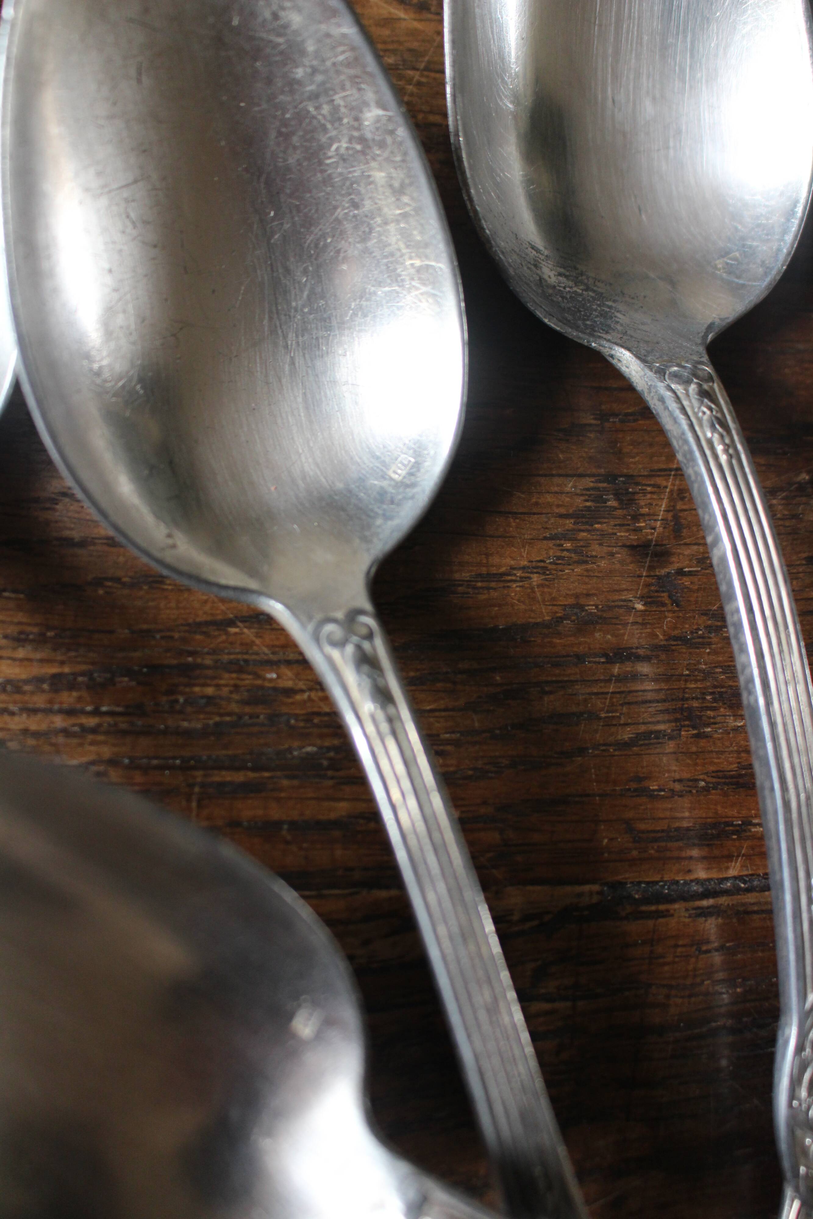 A set of 6 silver-plated metal soup spoons with foliage design.