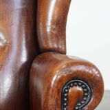 Sheep leather wingback chair with a red corduroy seat cushion and patina