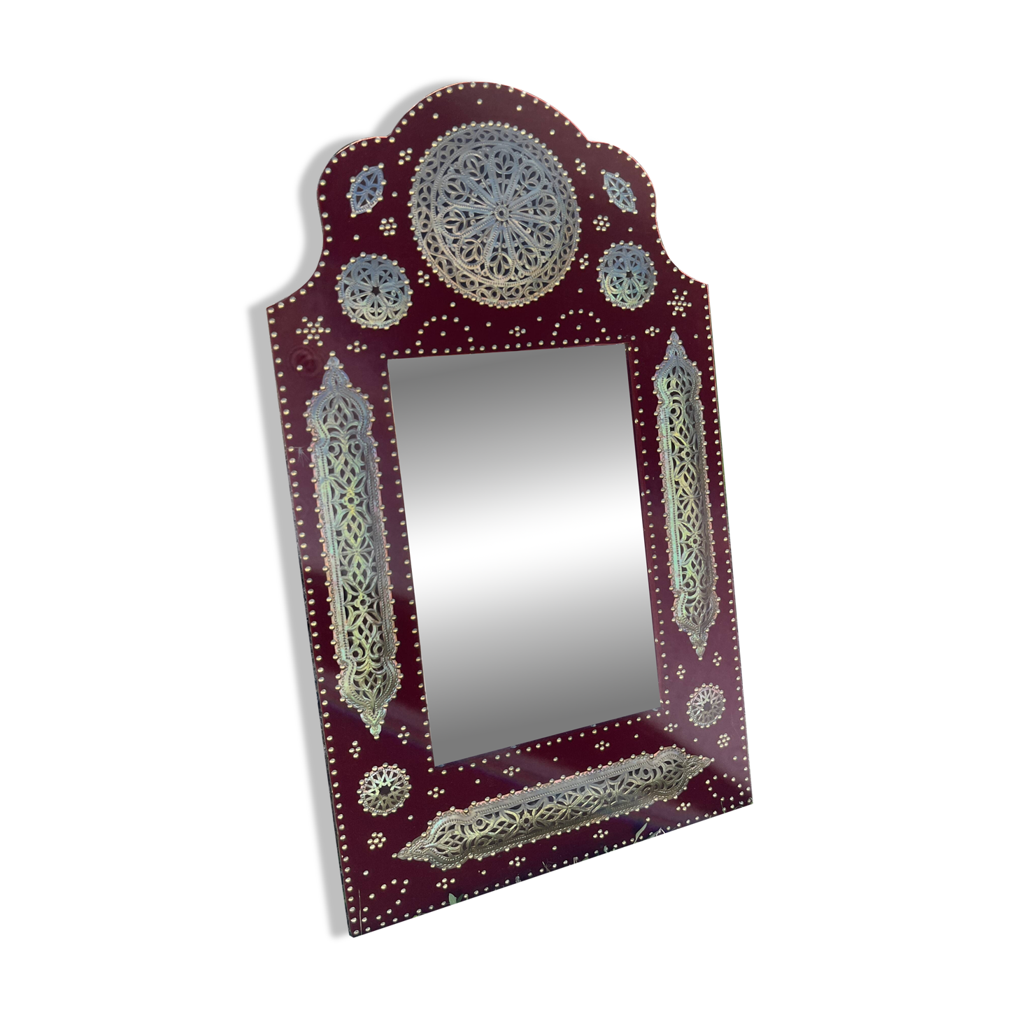 Large oriental mirror with embossed brass decoration on a red velvet background