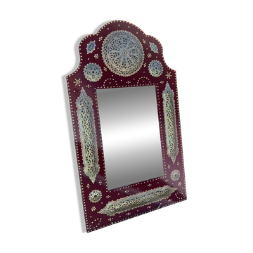 Large oriental mirror with embossed brass decoration on a red velvet background