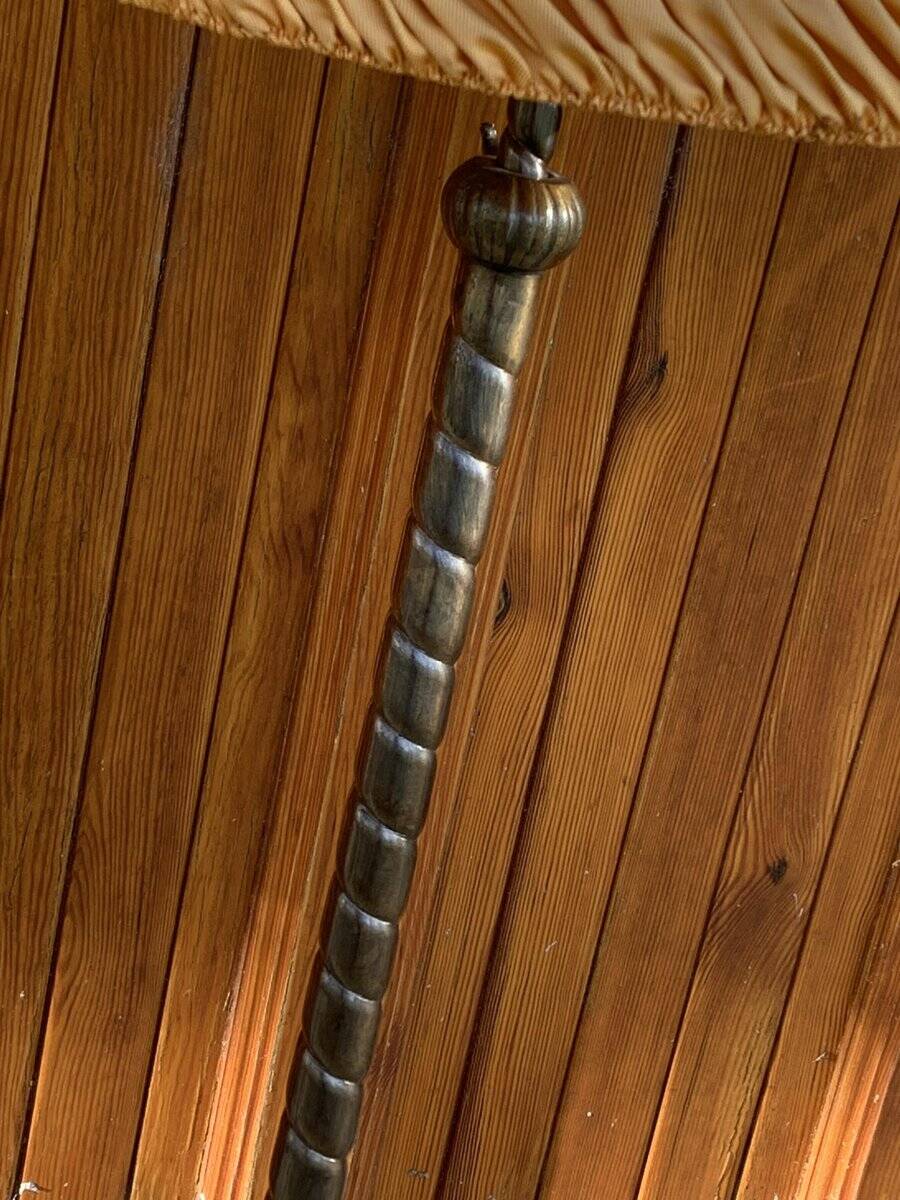Art Deco floor lamp in bronze metal with a straw yellow fabric shade, twisted shaft, and tripod base.