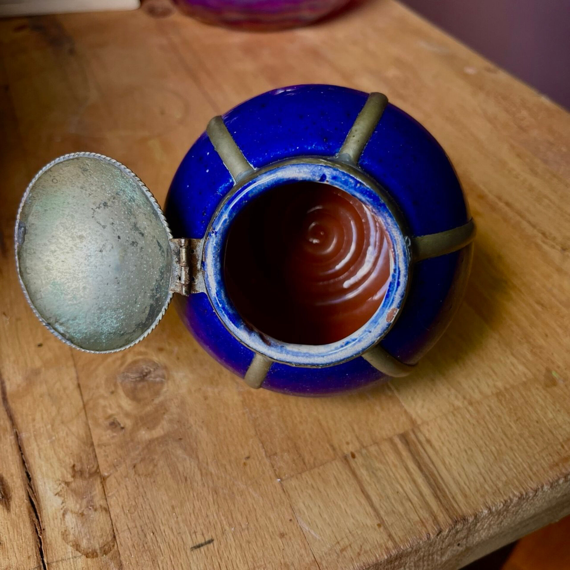 Small blue ceramic pot with metal frame and lid.