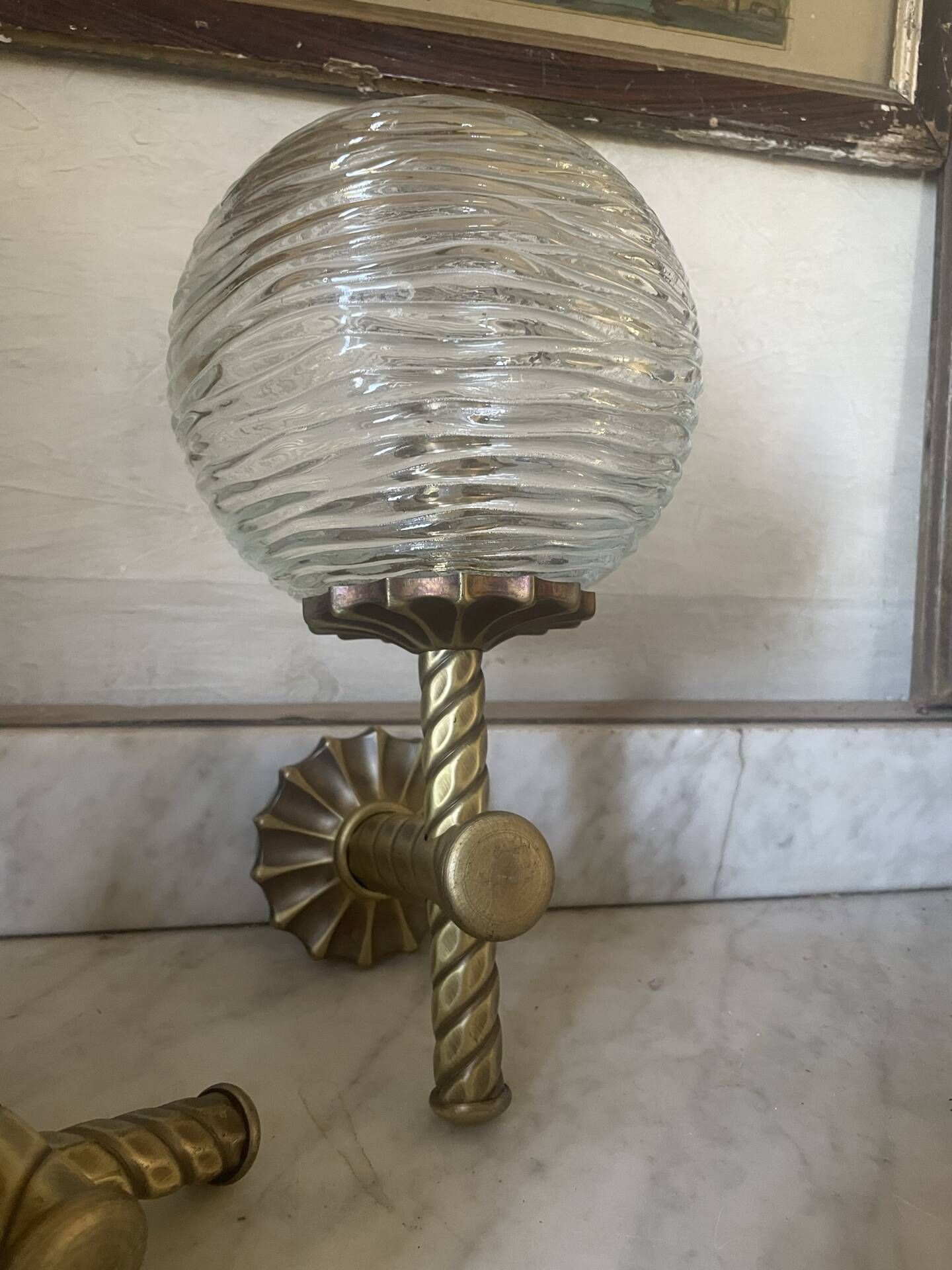 Pair of neoclassical wall sconces in twisted brass and ribbed glass.