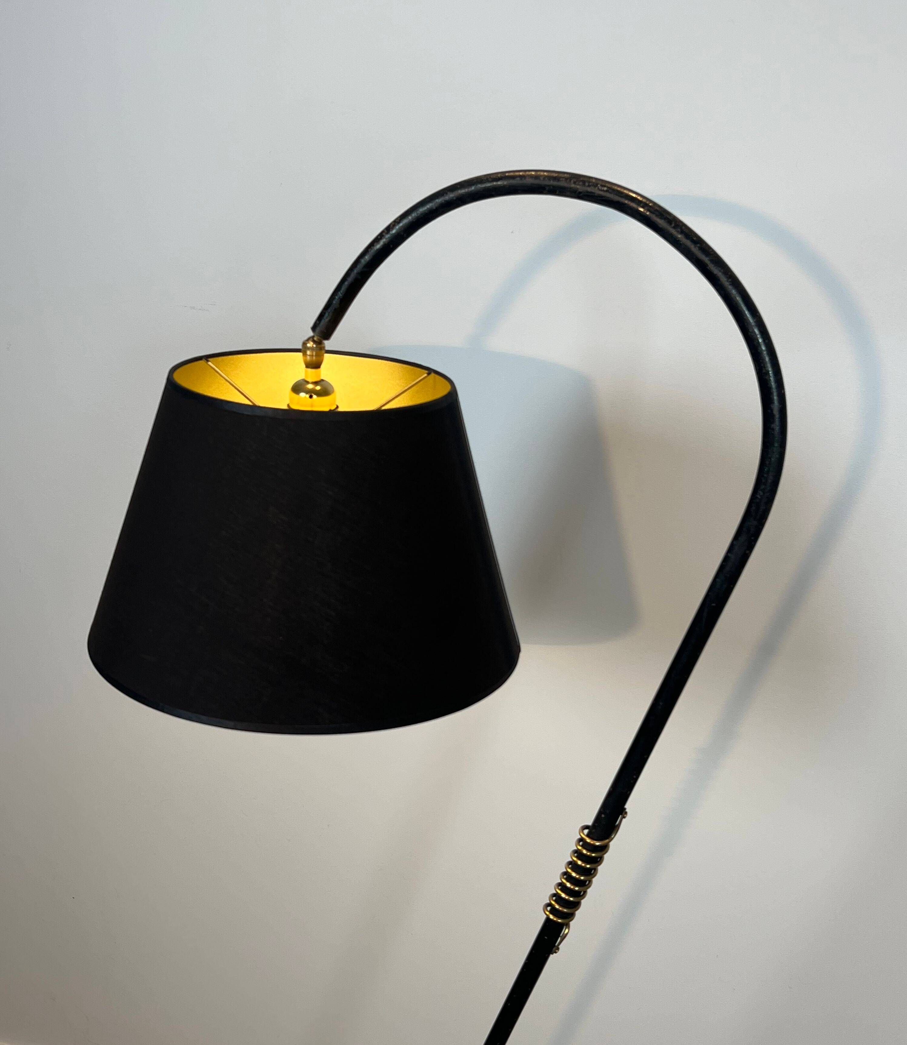 Design floor lamp in black lacquered metal and brass.