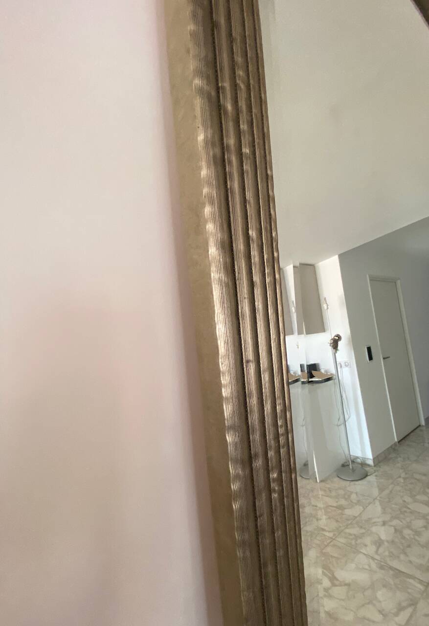 Textured embossed metal wall mirror with bevelled mirror.