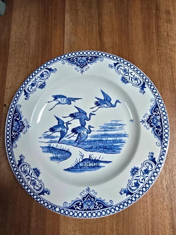 A pair of old flat plates with red and blue bird patterns.