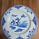 A pair of old flat plates with red and blue bird patterns.