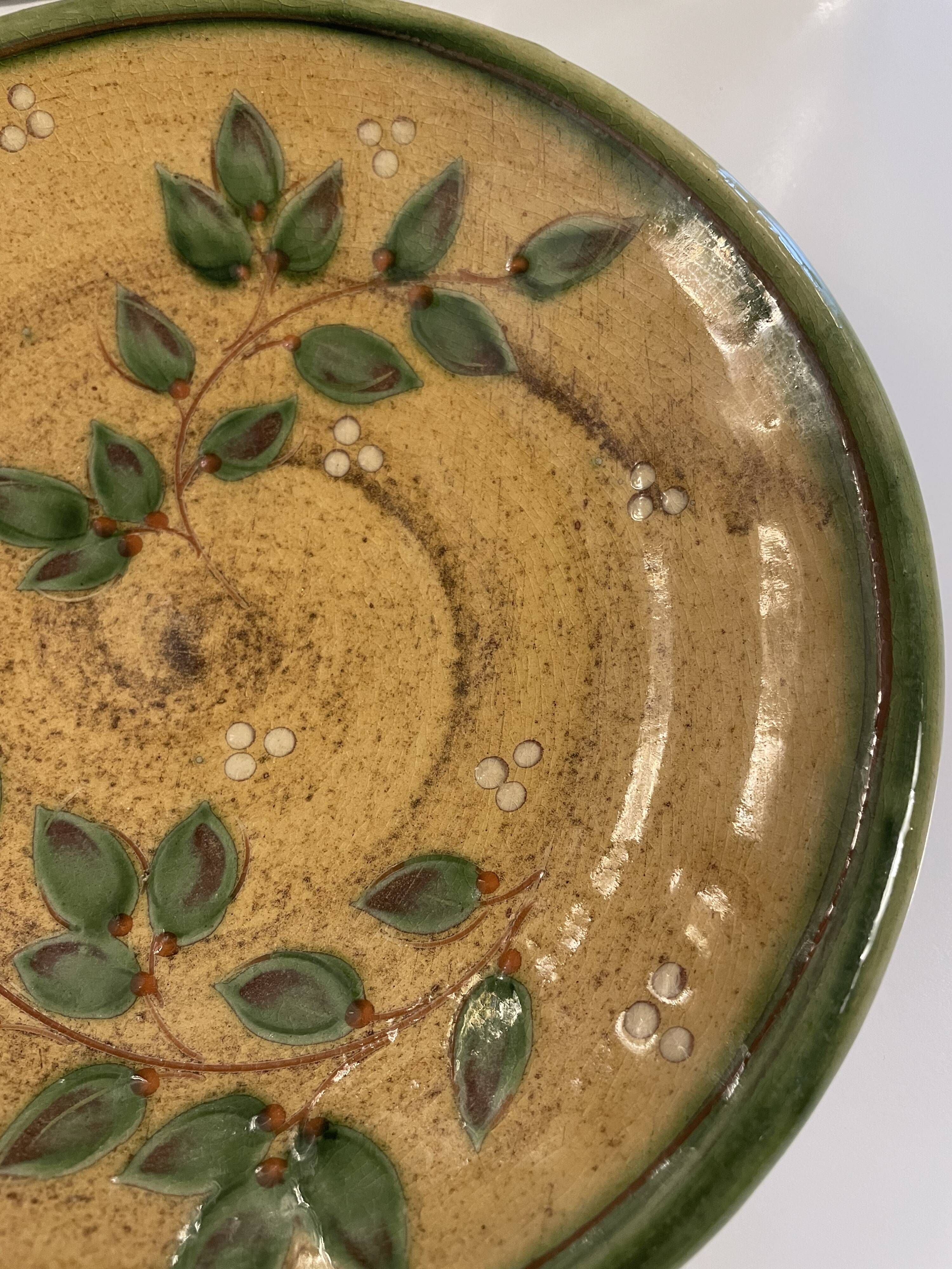 Decorative glazed terracotta plate with olive leaf pattern.