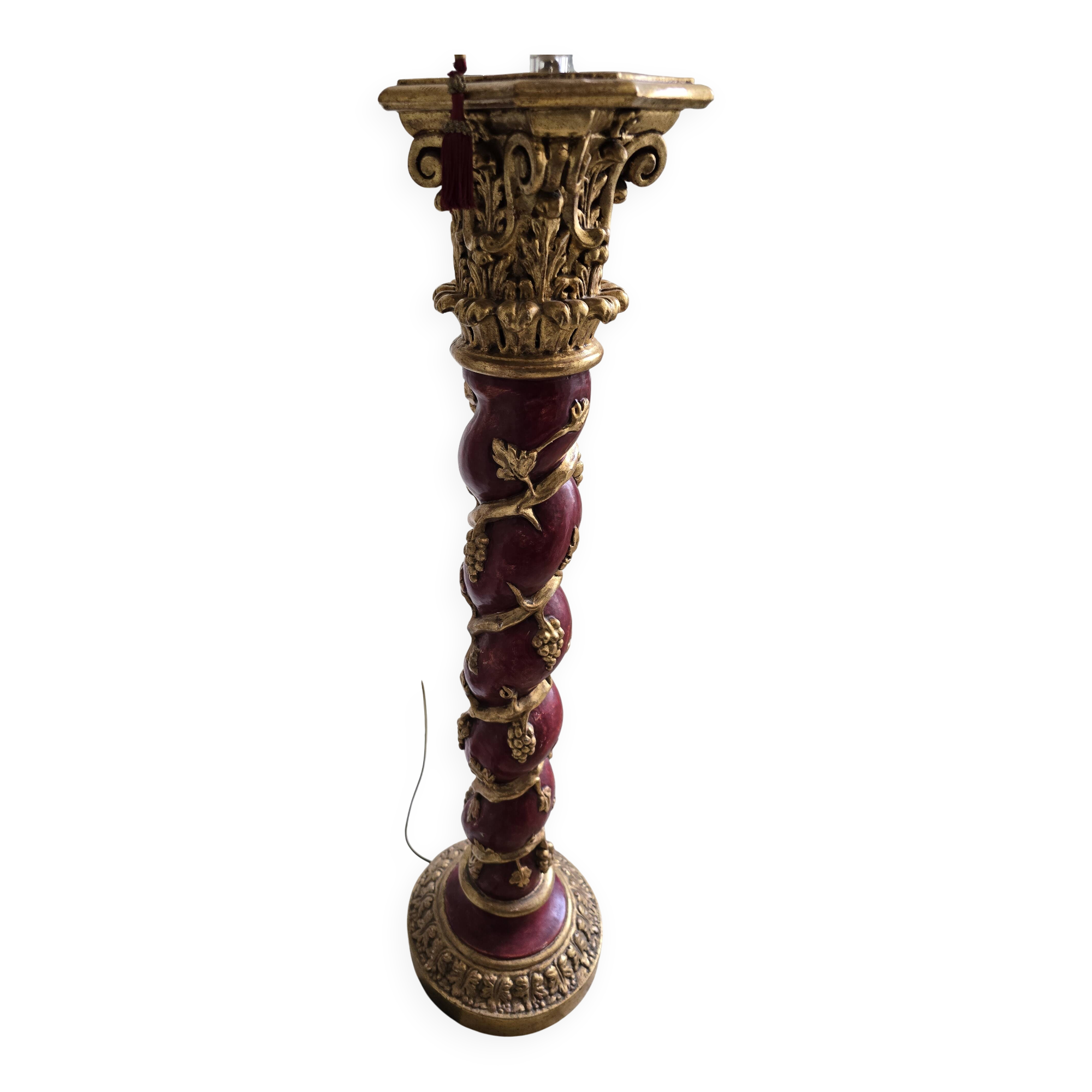 red and gold wooden column in the shape of a vine foot topped with a lamp