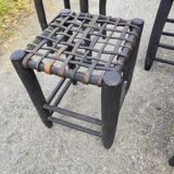 5 blackened wooden stools with woven leather seats by Nina Kaufmann