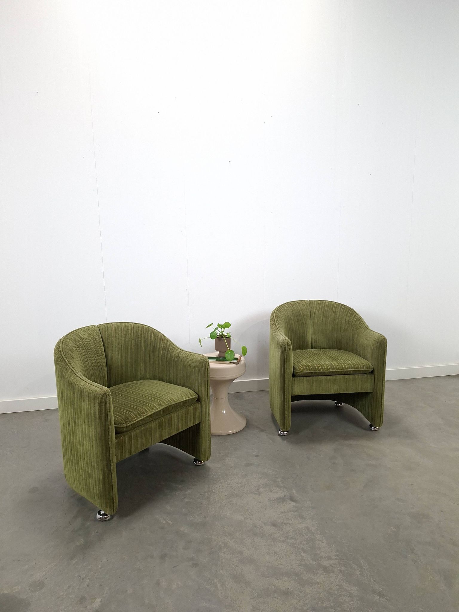Chaises de cocktail vertes avec des roues chromées.