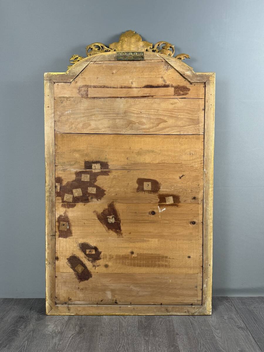 Large antique gilded wooden mirror in Louis XVI style with a sculpted pediment, 19th century.