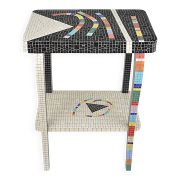 Table topped with a ceramic mosaic featuring an abstract design.