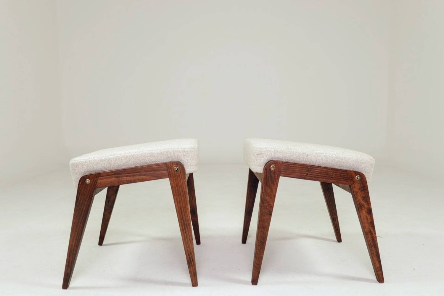 Pair of wooden stools with beige fabric.