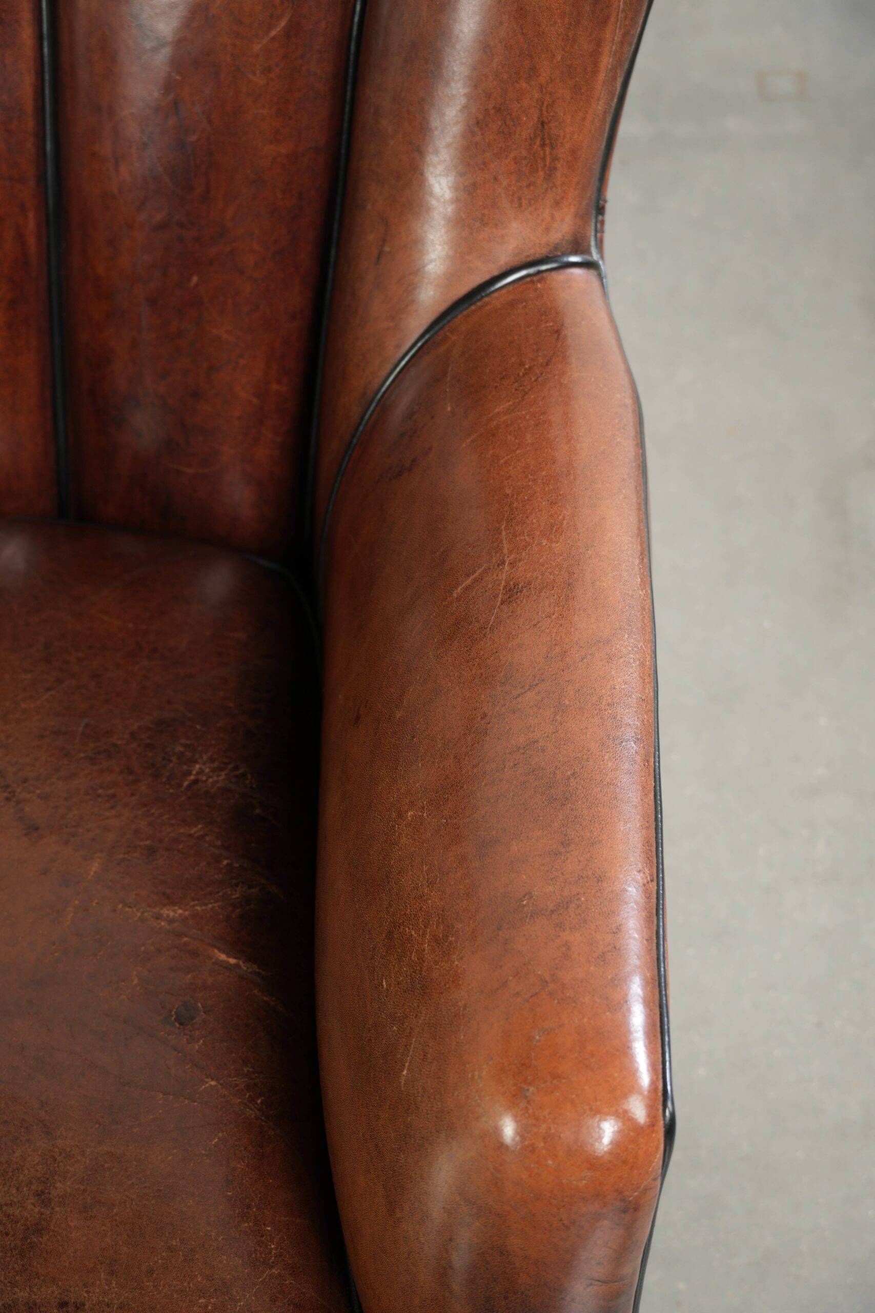 Fauteuil en peau de mouton confortable au design unique, fini avec un passepoil noir.