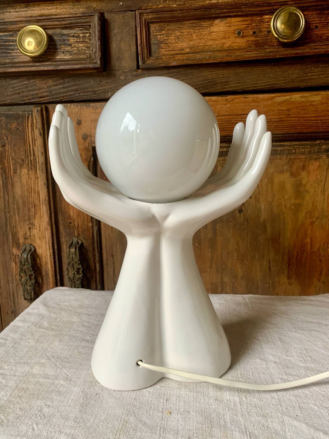 Ceramic table lamp depicting two hands holding a globe, 1980