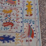 White suzani kilim rug with embroidered colorful patterns