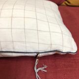Beige linen cushion with checkered pattern and shiny dark gray piping