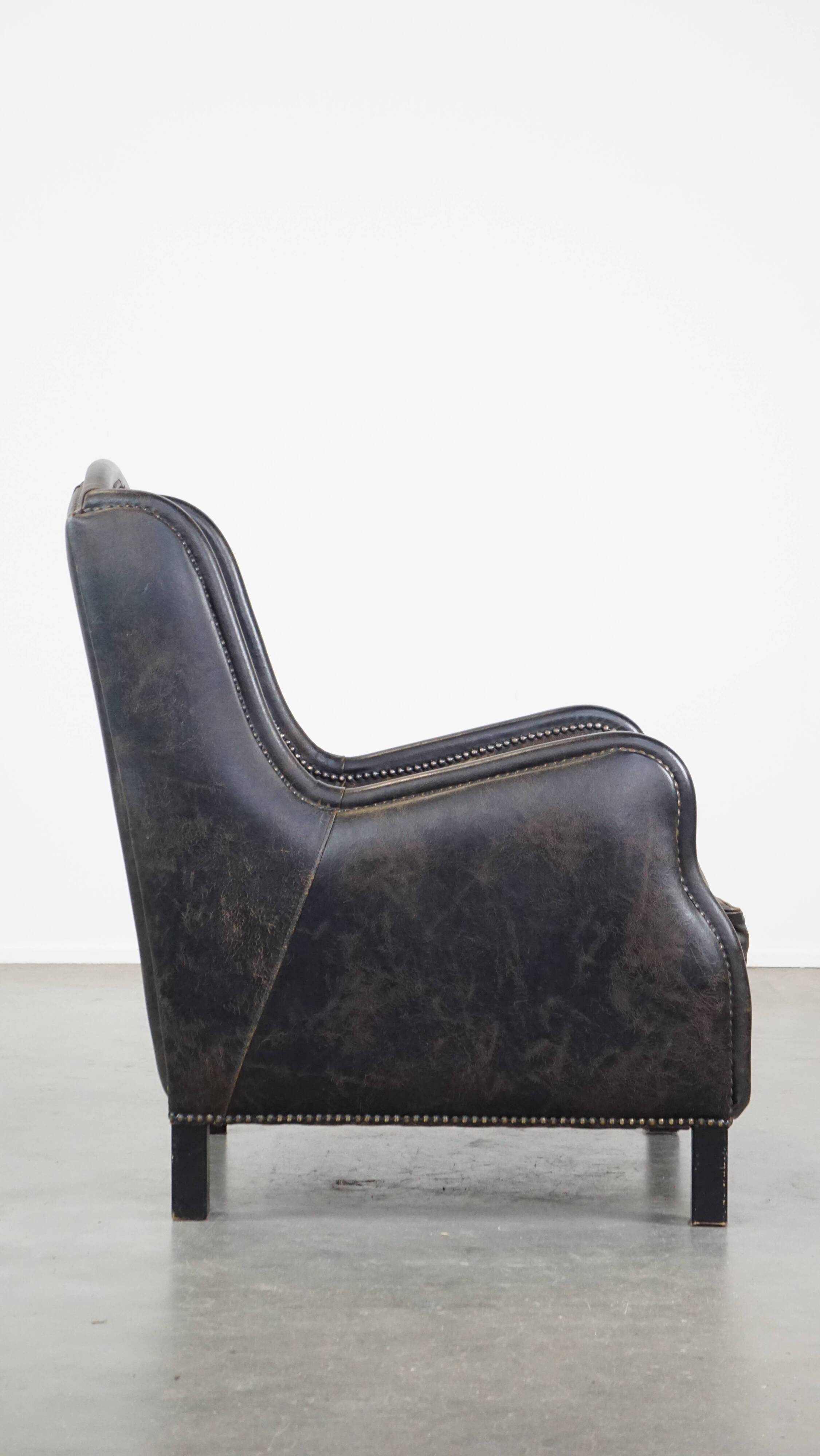 Black cow leather armchair in industrial style finished with decorative nails