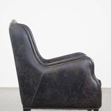 Black cow leather armchair in industrial style finished with decorative nails