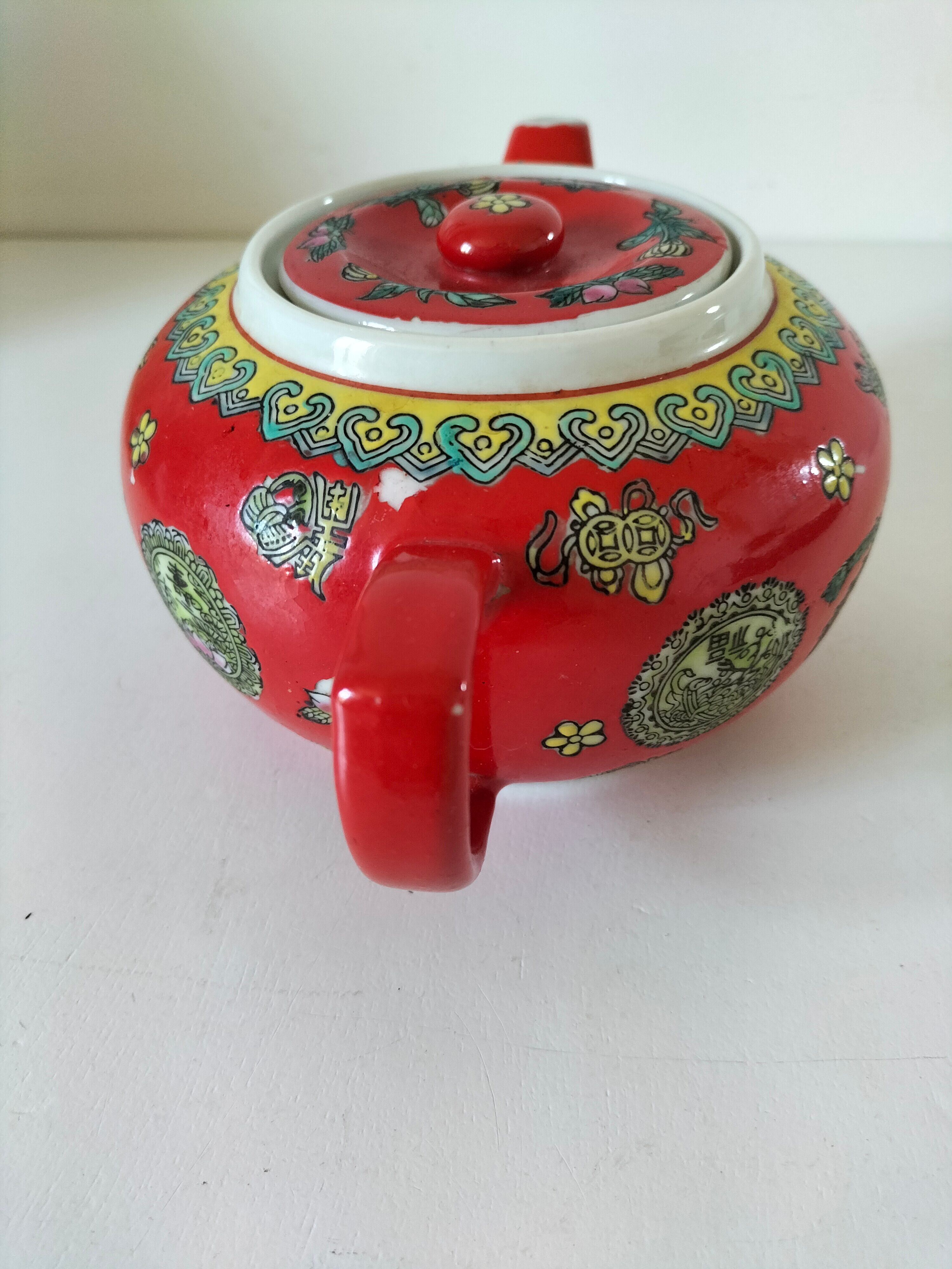 Vintage red Chinese teapot decorated with dragons and symbols.