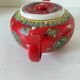 Vintage red Chinese teapot decorated with dragons and symbols.