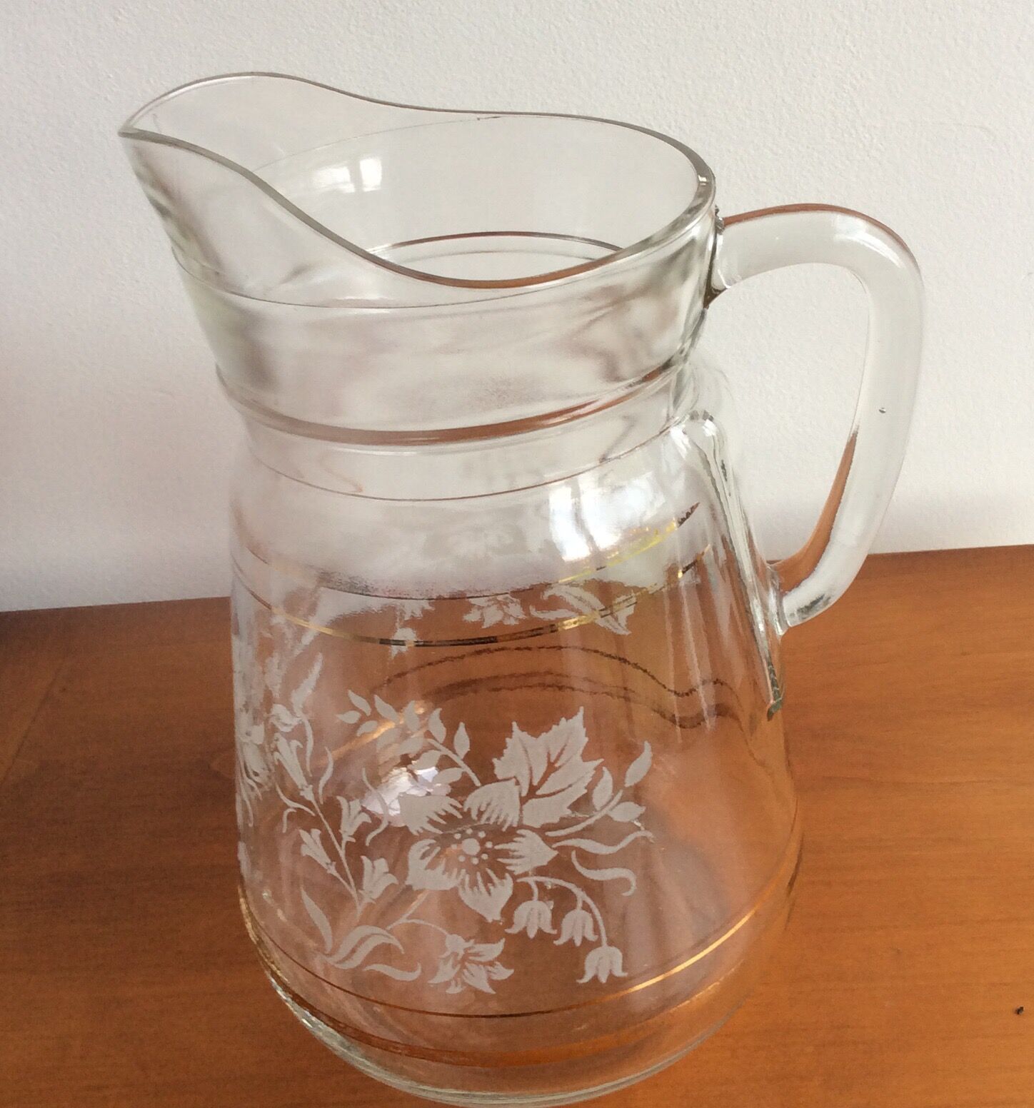 Old glass water pitcher with white flowers in relief with gold edging