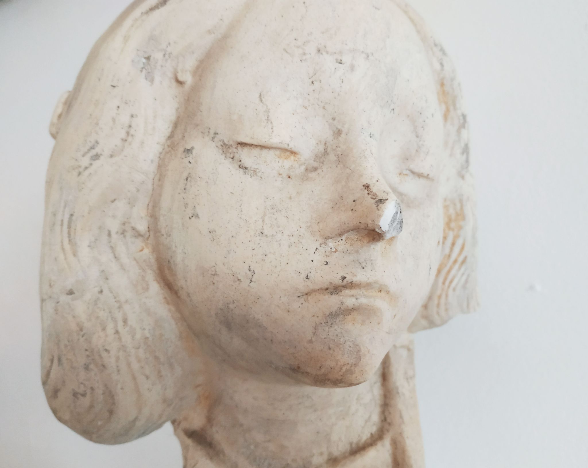 Bust of woman in plaster on pedestal with inscription