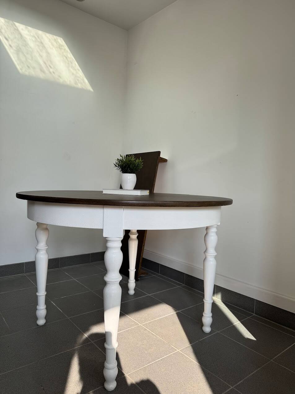 Restored solid wood round table with integrated extensions.