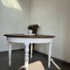 Restored solid wood round table with integrated extensions.