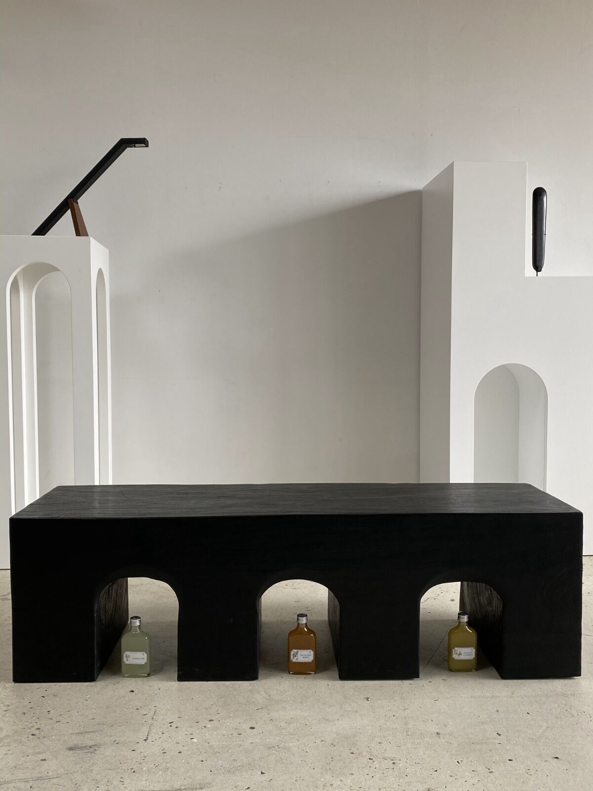 Black solid monoxyl wood bench carved into 3 arches