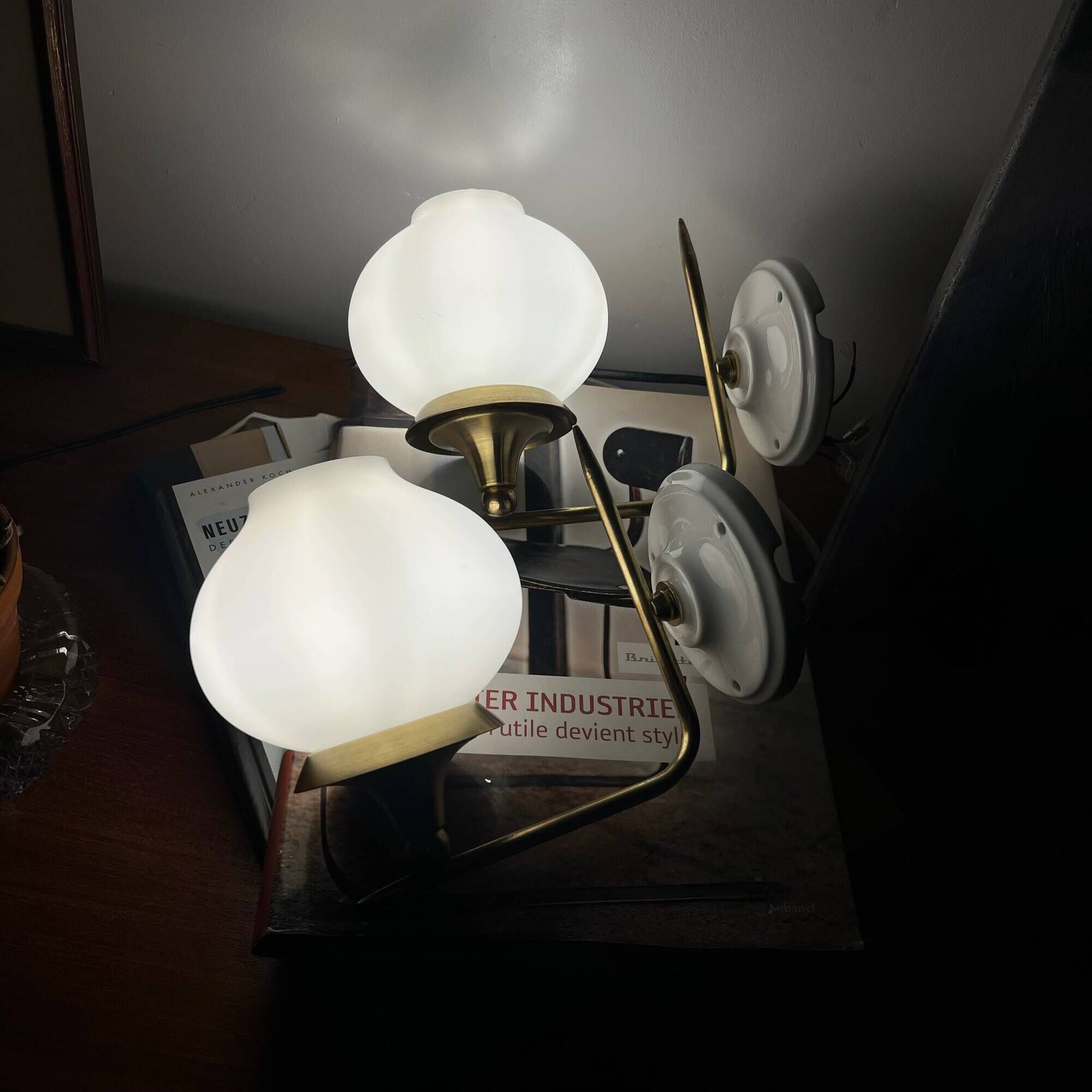 Pair of vintage wall sconces in brass with white glass globe shades.