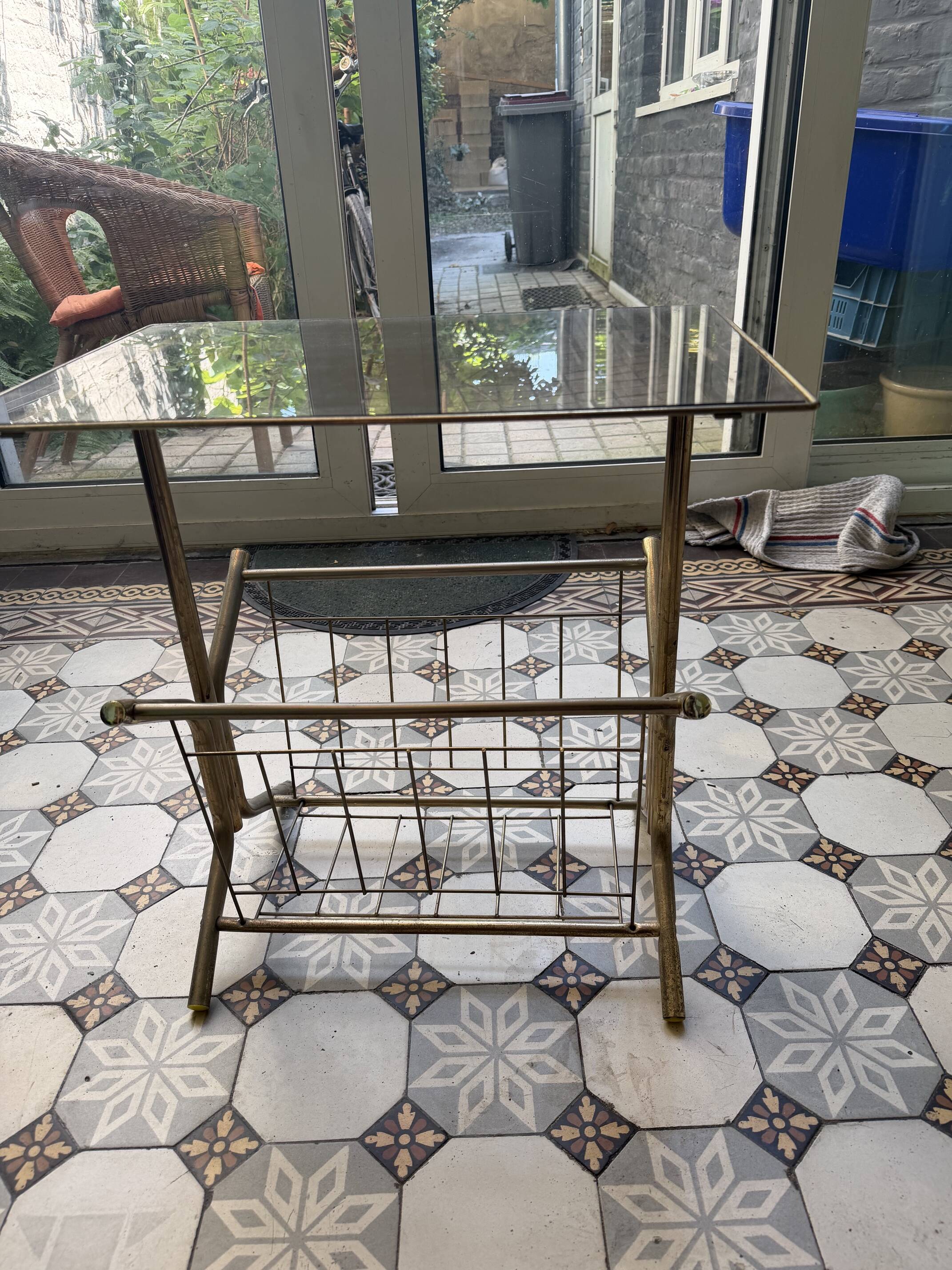 Vintage style side table with magazine holder, gold metal and glass top.