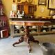 Table with a carved wooden frame and grey marble top on wheels, measuring 130 x 82 cm.