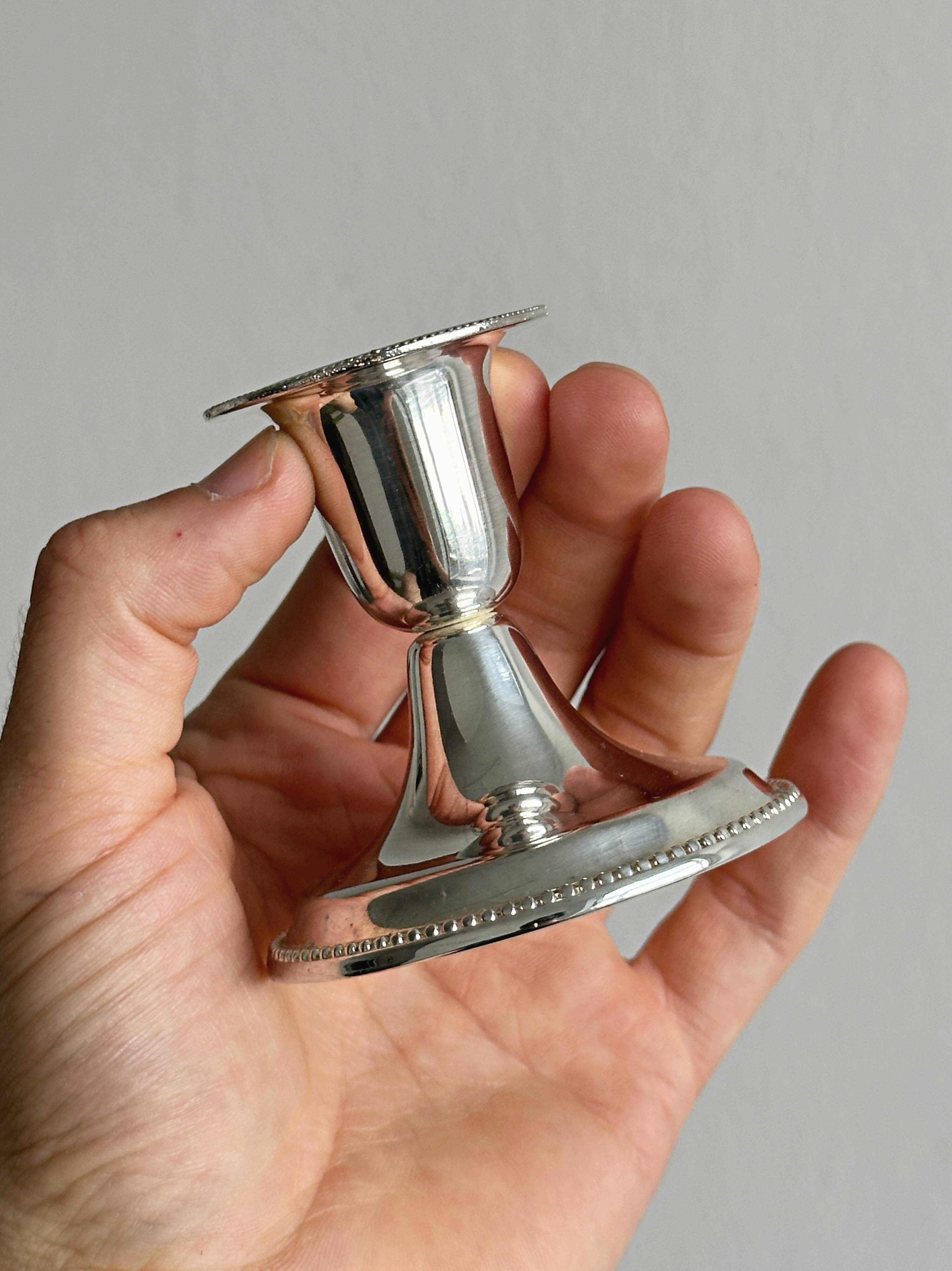 A pair of small silver-white metal candle holders.