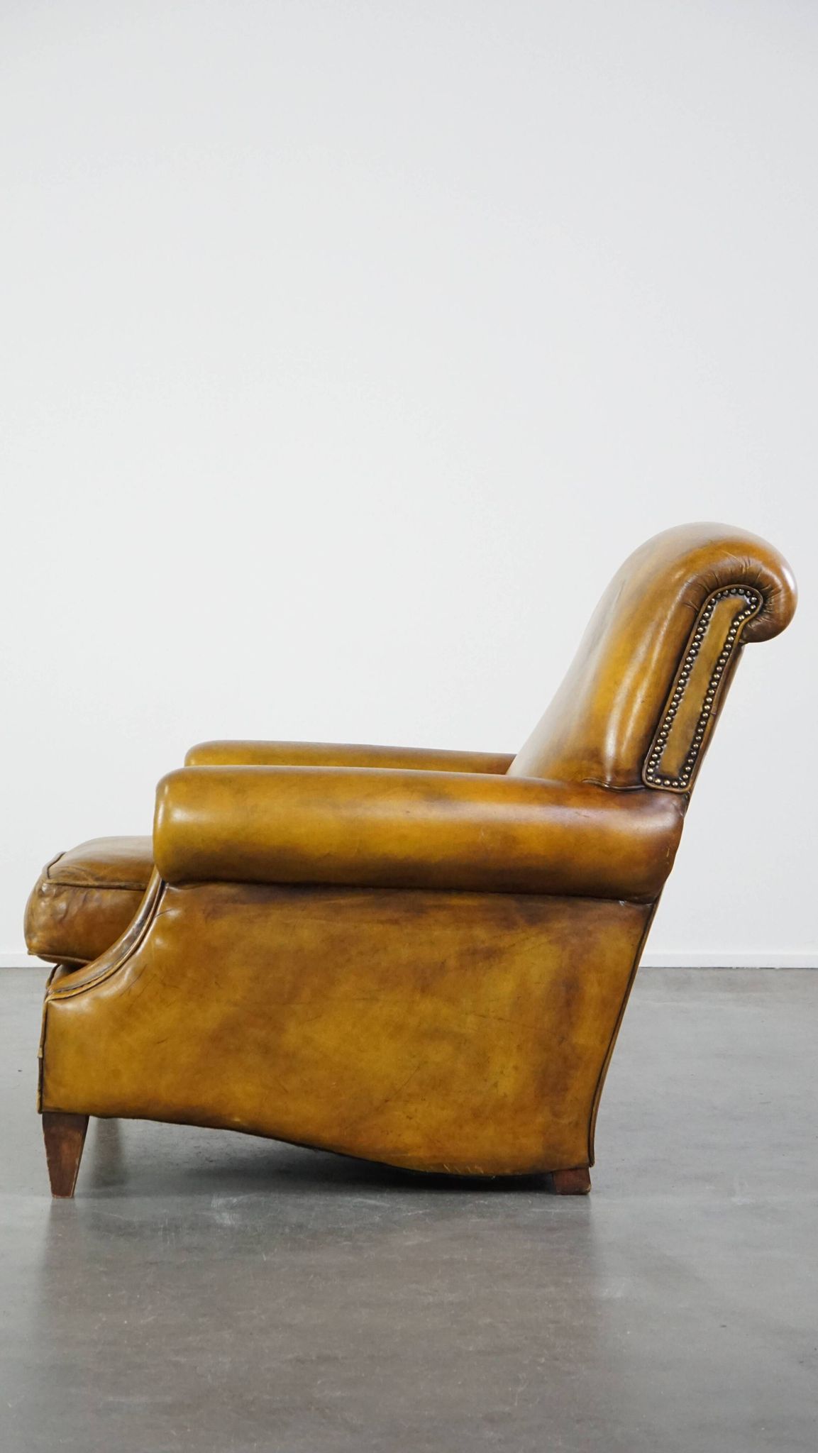 Comfortable large yellow English-style leather armchair with a fine finish and decorative nails