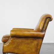 Comfortable large yellow English-style leather armchair with a fine finish and decorative nails