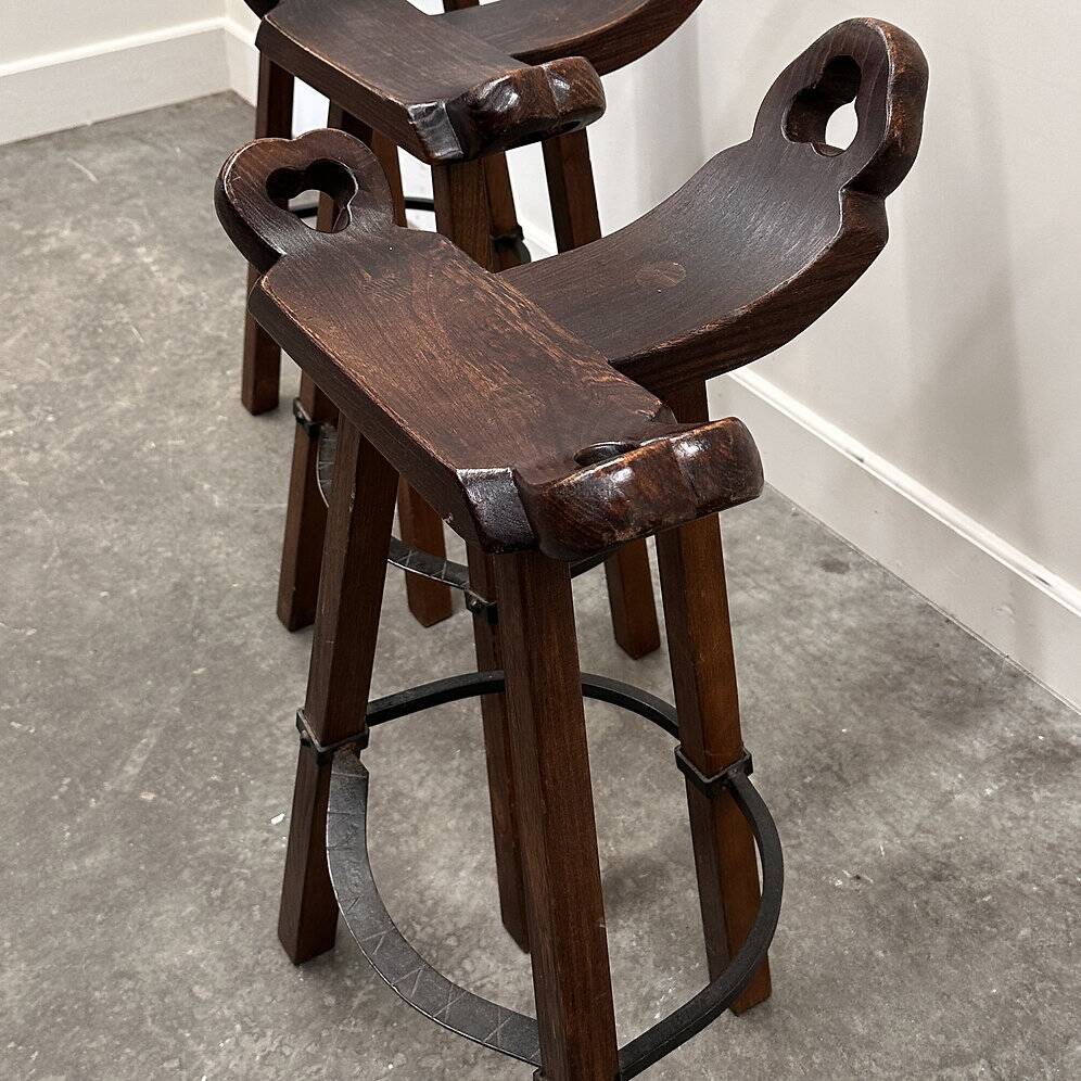 Set of 3 rustic carved oak bar stools with iron footrests, 1970s