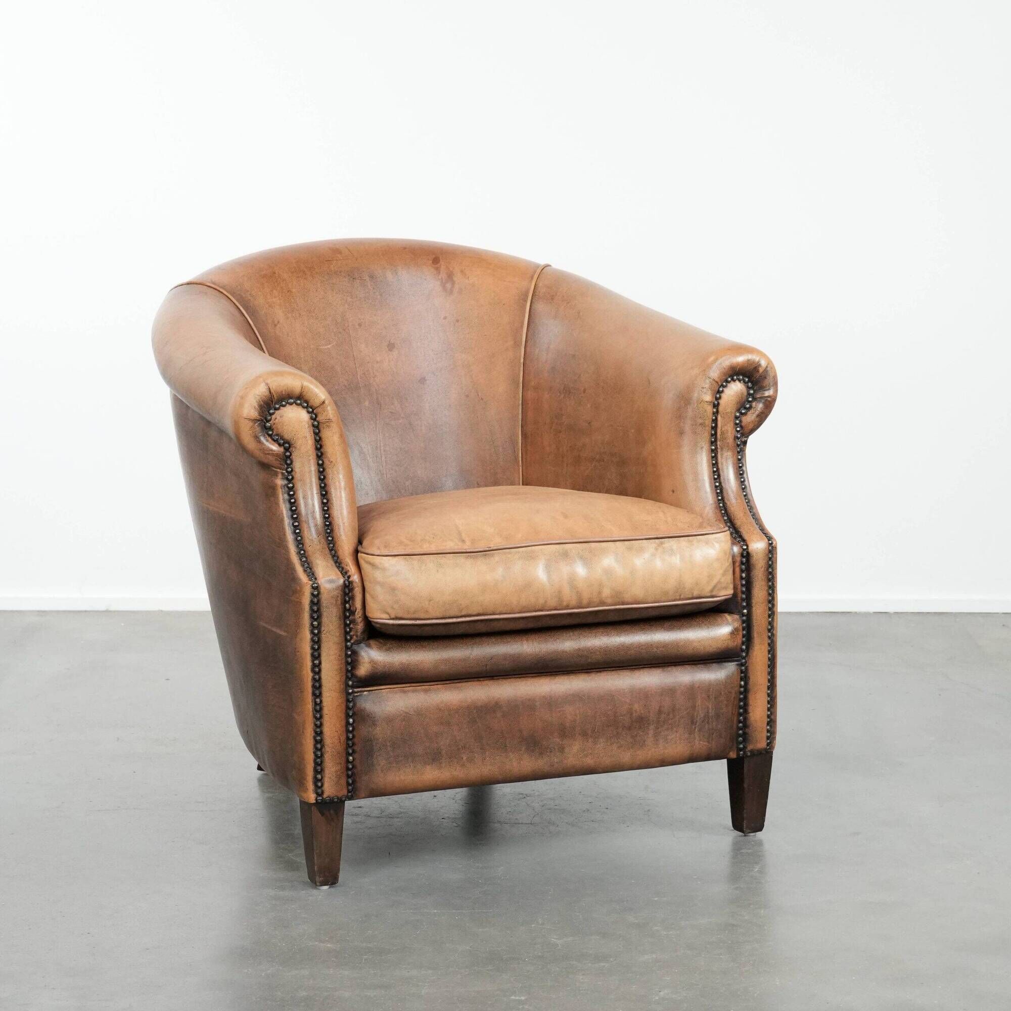 Club chair made of sheepskin leather finished with decorative nails