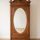 Antique solid wood wardrobe with an oval mirror.
