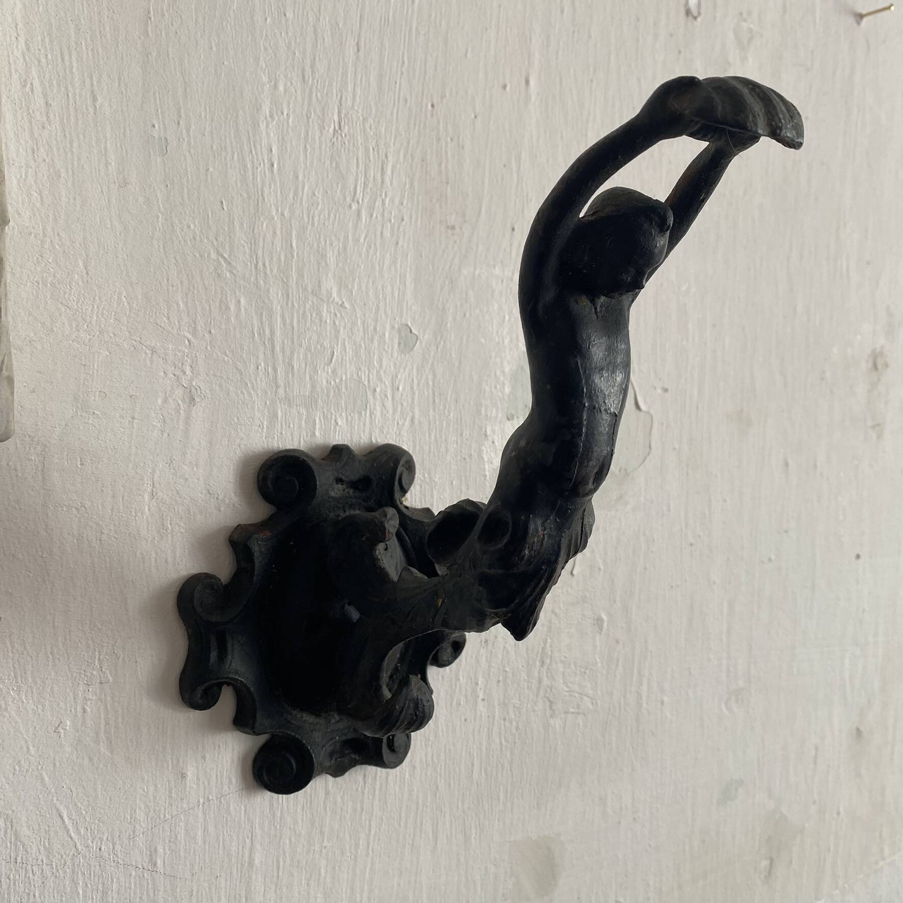 Antique cast iron coat hook with swimmer and shell basin.