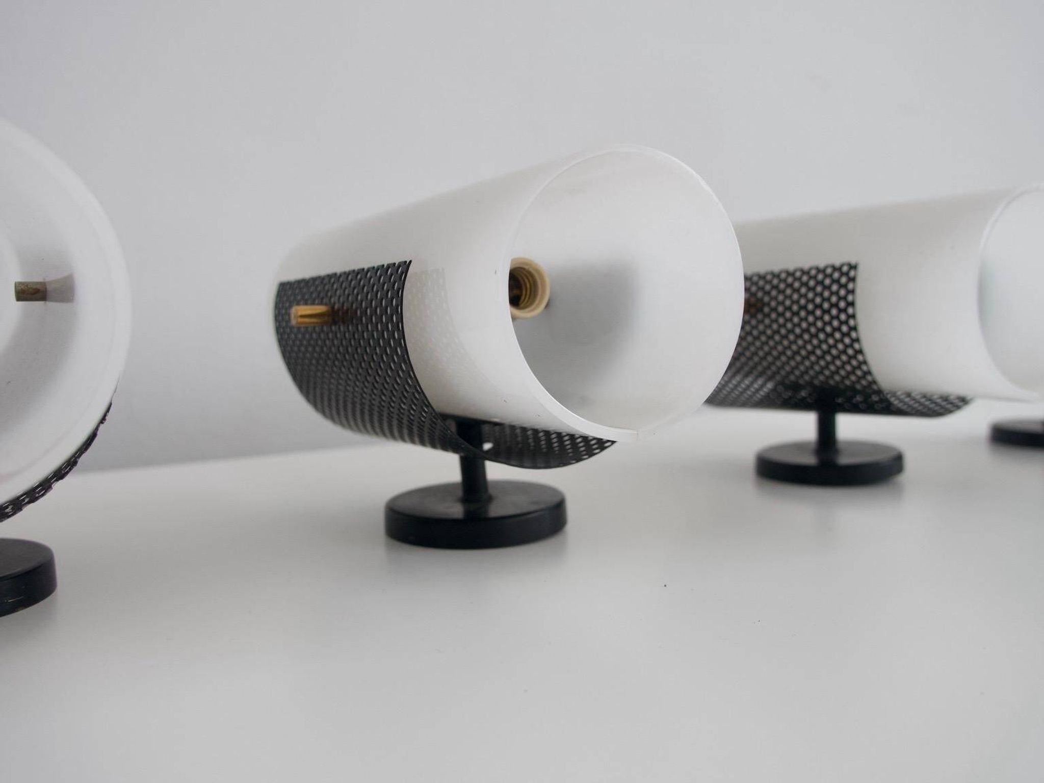 Set of four wall lights in white plexiglass and perforated black metal.