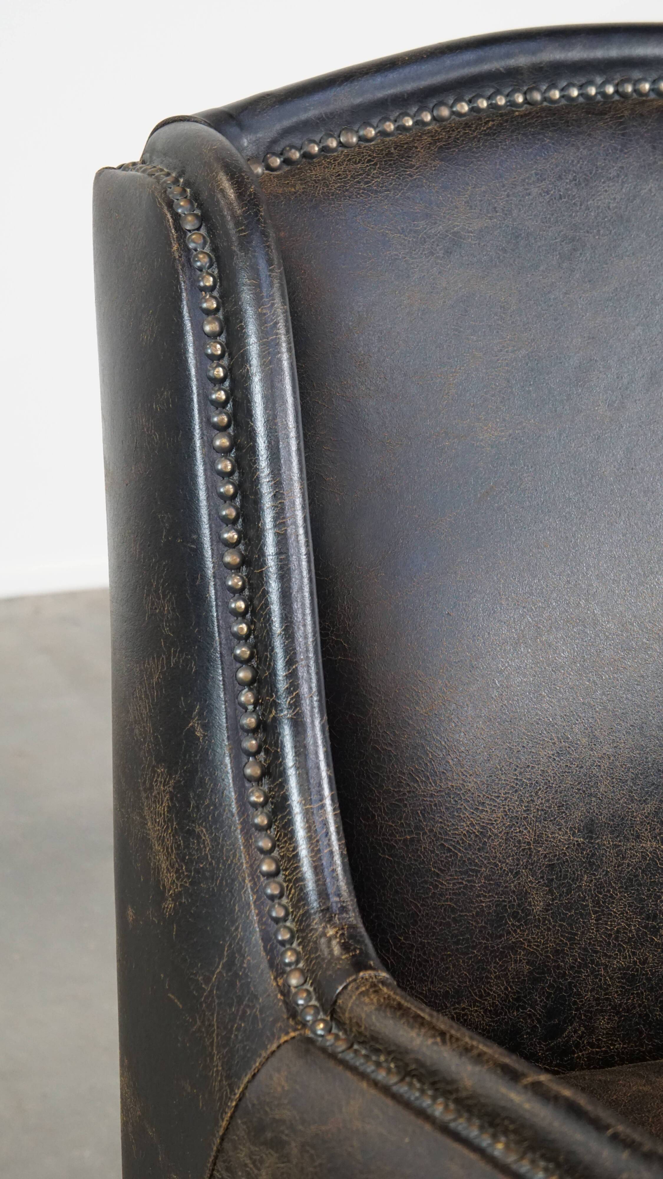 Black cow leather armchair finished with decorative nails, industrial style