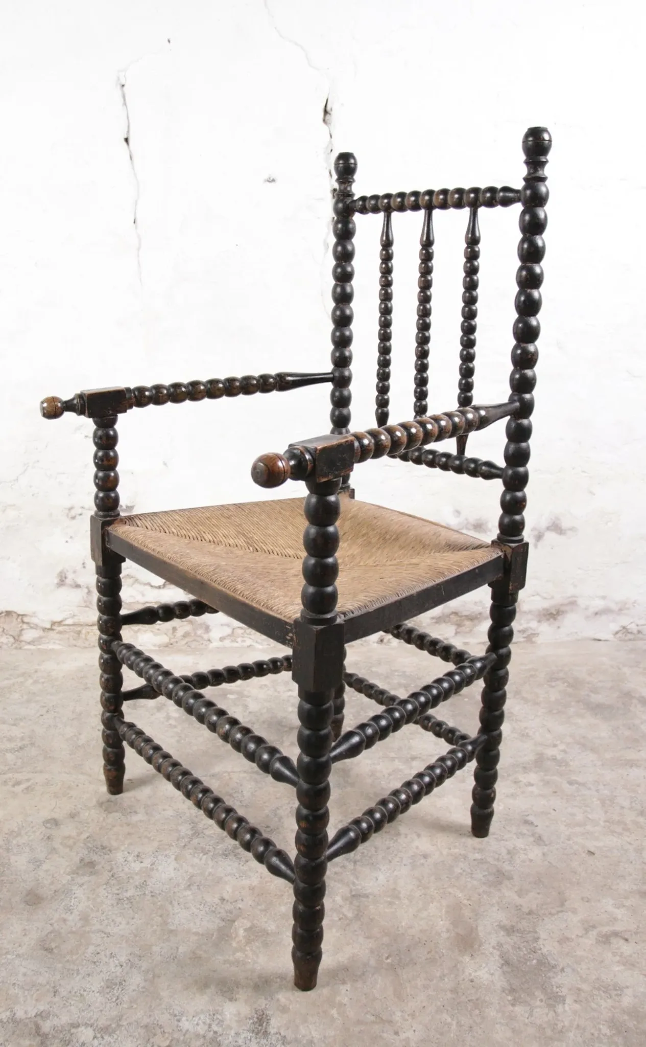 Black bobbin chair with armrests and rush seat – ca. 1900-1930