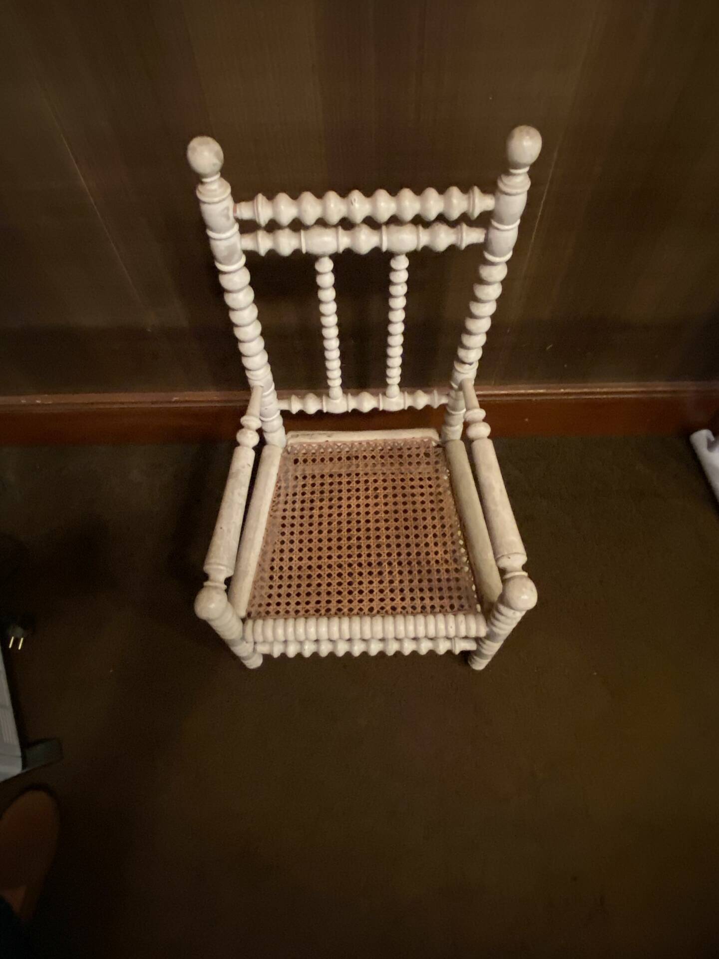 Antique wooden child's chair with turned legs and caning, white patina.