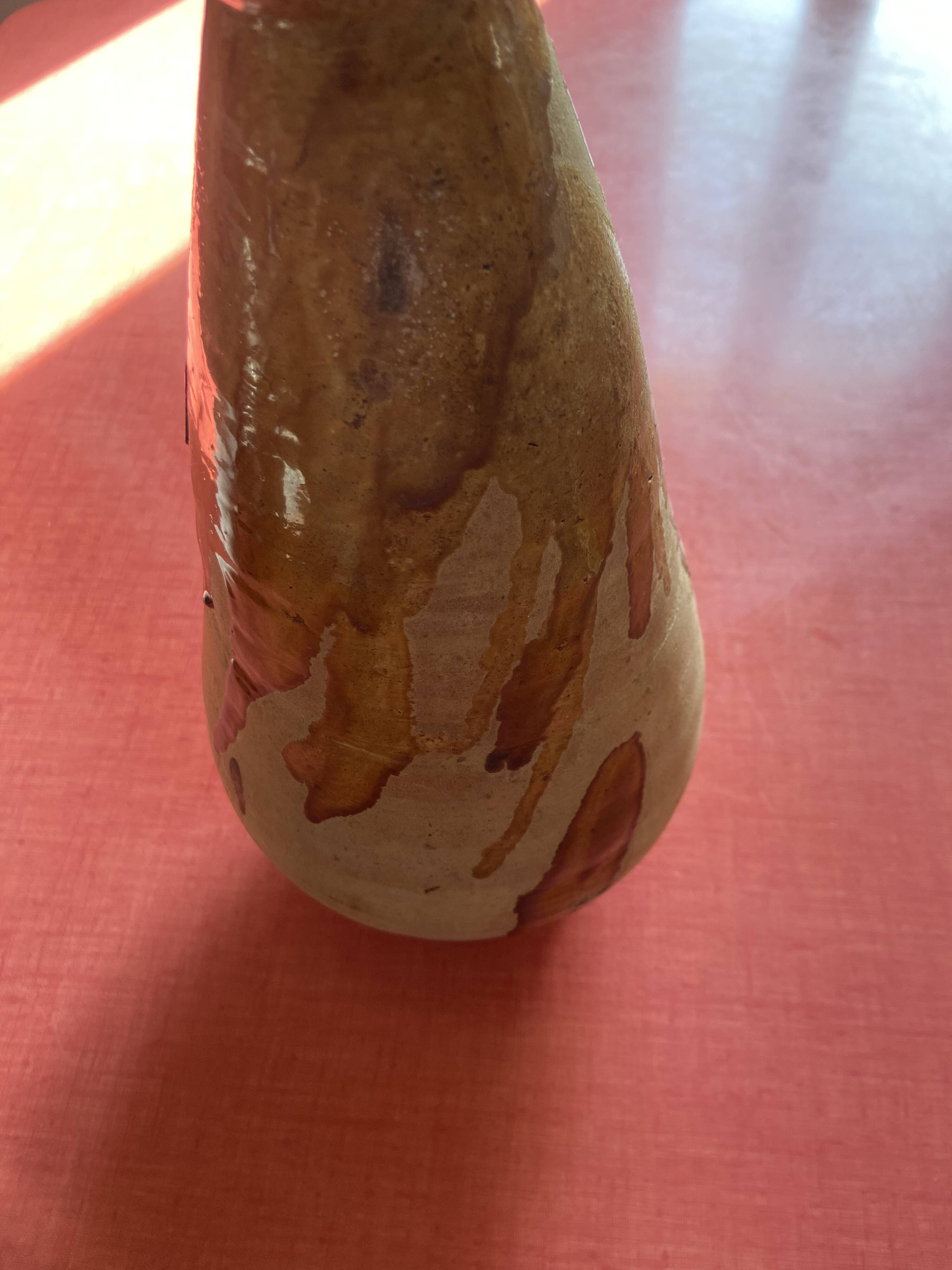 Large antique pottery bottle in glazed terracotta with drips.