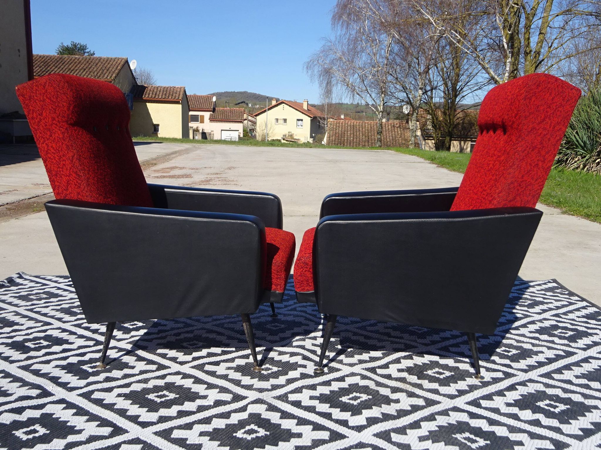 Pair of vintage armchairs in black faux leather and red fabric.